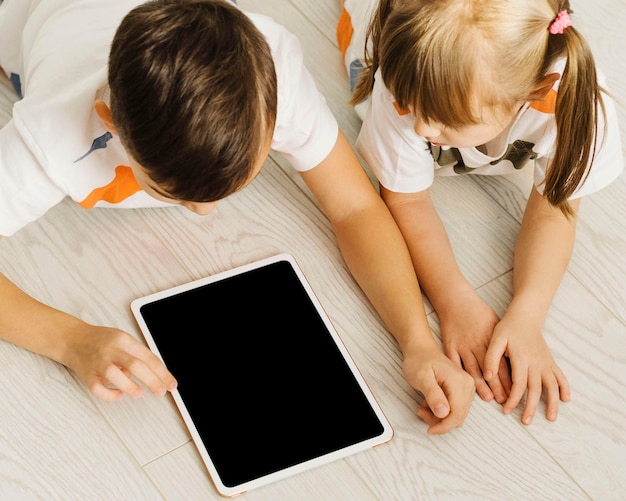 High view siblings using a digital tablet