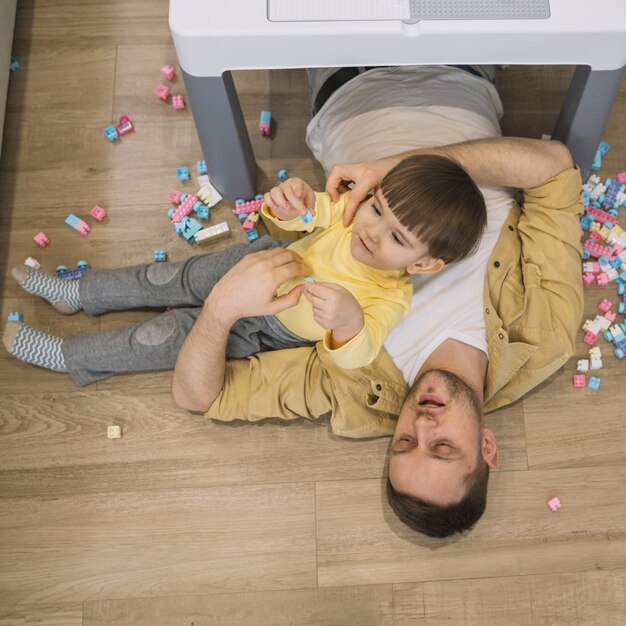 High view son and father laying on the floor