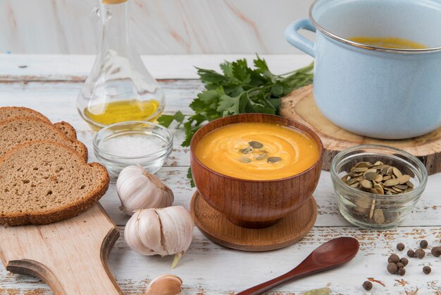 High view wooden table with soup and slices of bread