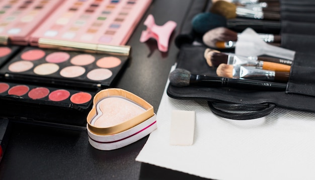 Free photo highlighter powder and makeup brushes on table