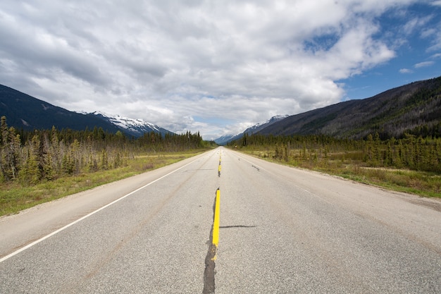 Highway surrounded by a mountainous scenery under the cloudy sky in Canada