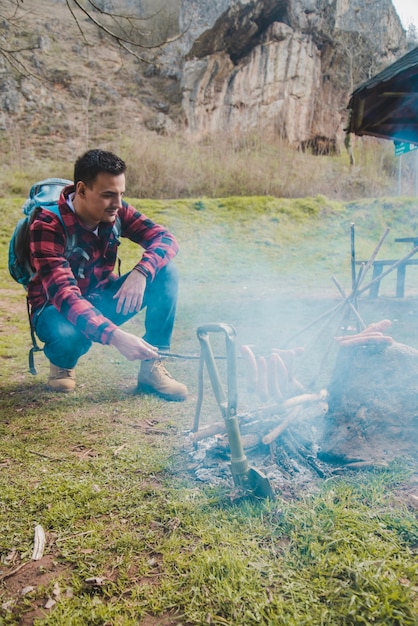 Hiker by the fire preparing sausages