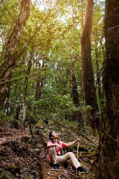 Free photo hiker sitting on a hill in jungle and looking above