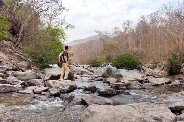 Hiker on stone in wild river