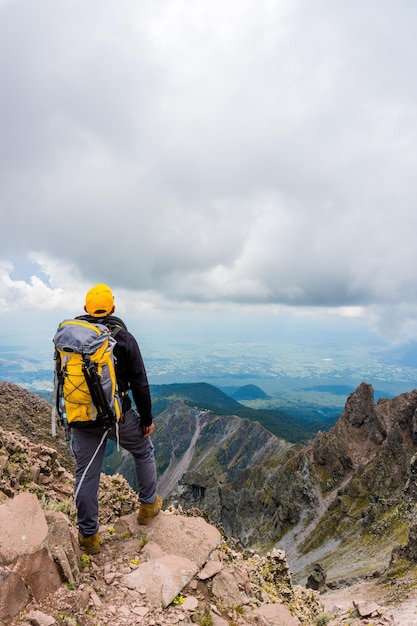 Hiker with a backpack standing on the top of the mountain