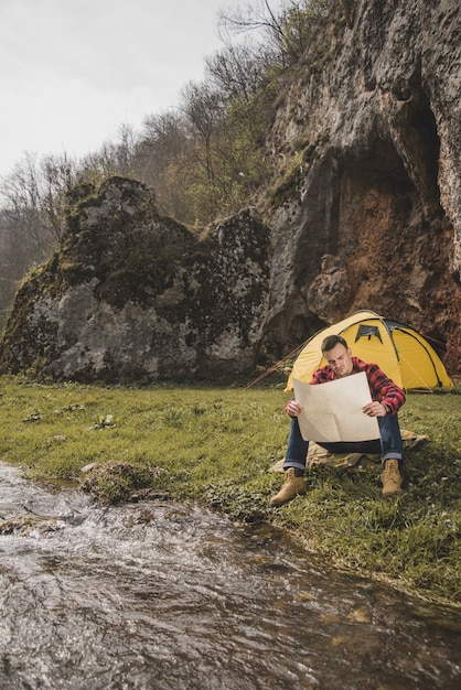 Free Photo hiker with map sitting next to the river