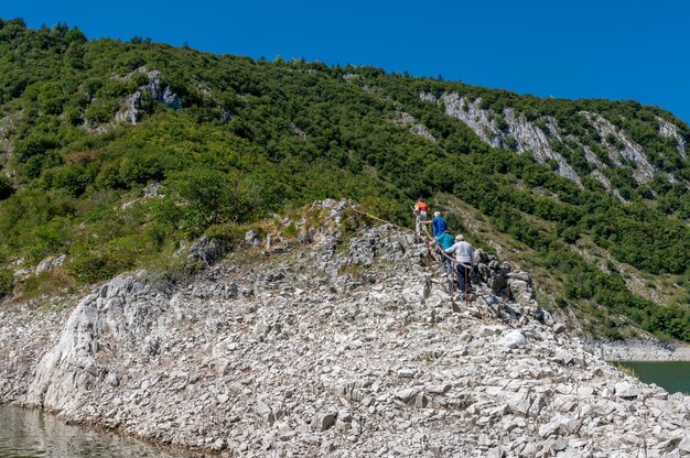 Hikers climbing the rocky hill under the blue sky