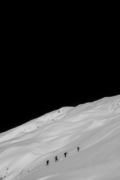 Free photo hikers walking up a steep snowy hill at night