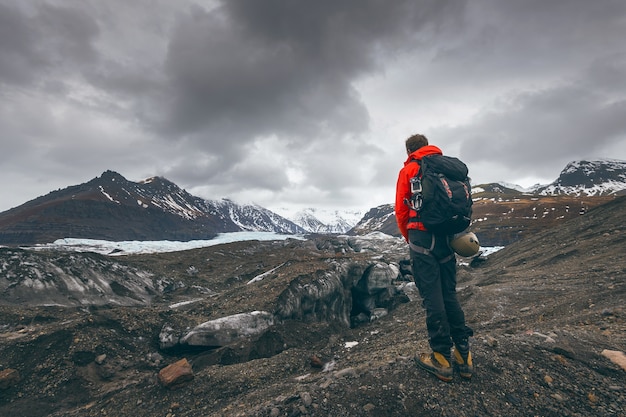 Hiking adventure travel man watching glacier in Iceland.