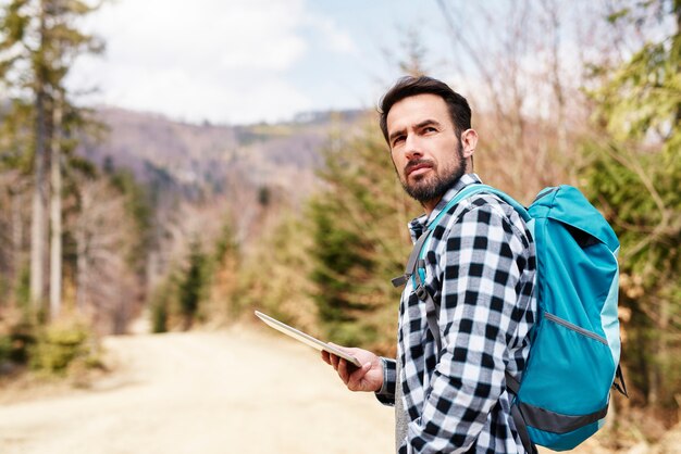 Free photo hiking man with backpack and tablet enjoying at view