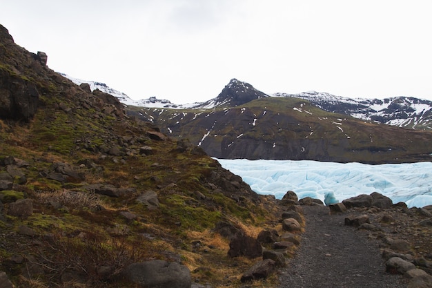 Hills covered in the snow and grass surrounded by a frozen lake in Vatnajokull National Park