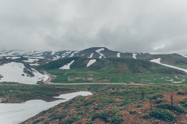 Free photo hills half covered with snow in cloud day