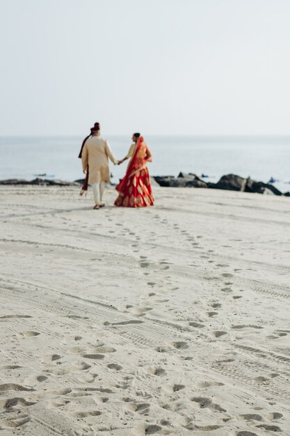 Hindu wedding couple walks along the ocean shore