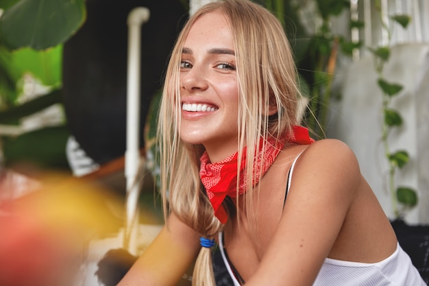 Hipster girl with bandana on neck poses in cafe