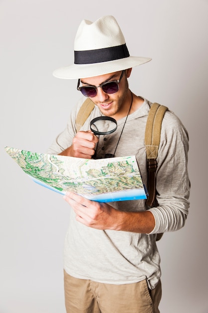 Hipster man using magnifying glass to read map