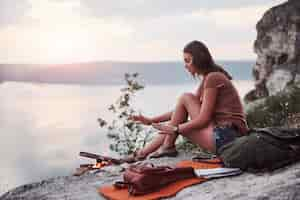 Free photo hipster young girl with backpack enjoying sunset on peak of rock mountain.