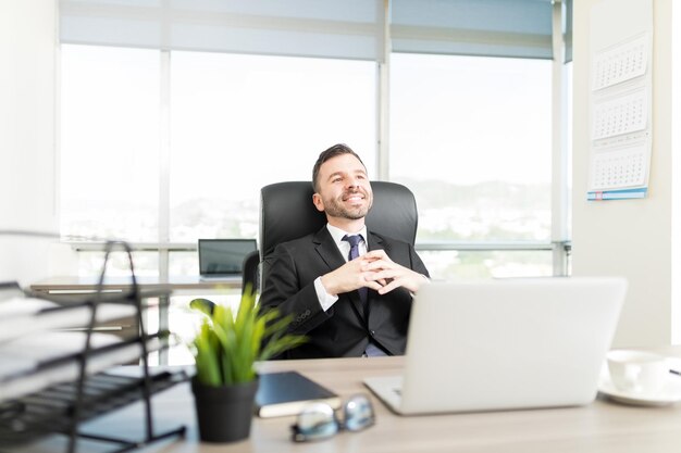 Hispanic executive manager thinking about something good while sitting in office