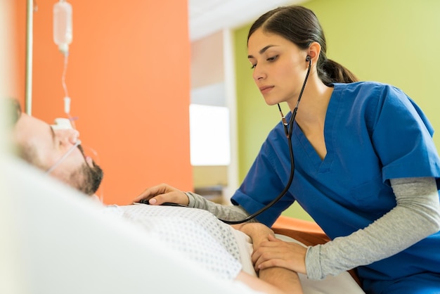 Hispanic female doctor examining patient with stethoscope at hospital