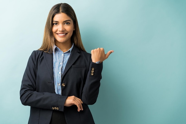 Hispanic female executive gesturing at copy space while making eye contact in studio