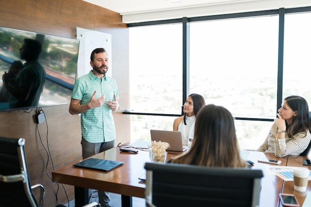 Free photo hispanic manager sharing ideas with team in meeting room at office