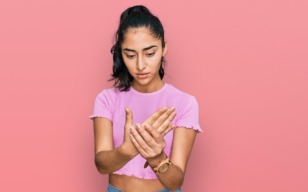 Hispanic teenager girl with dental braces wearing casual clothes suffering pain on hands and fingers arthritis inflammation