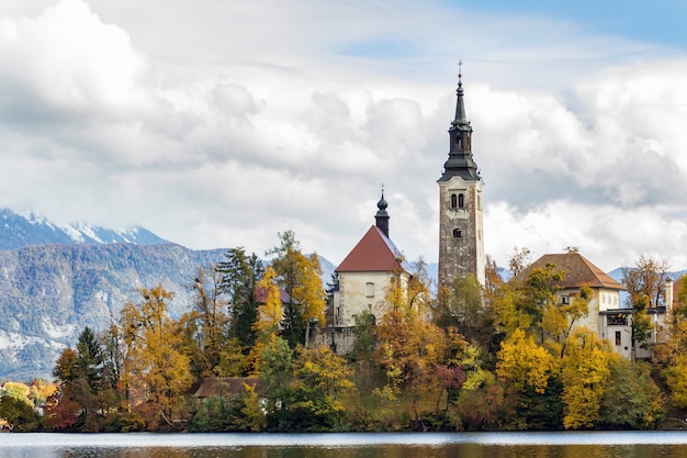 Historic castle surrounded by green trees near the lake under the white clouds in Bled, Slovenia