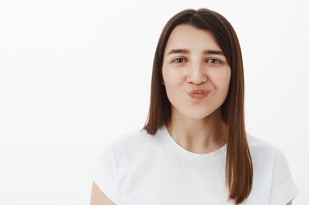 Hmm sounds tasty. Portrait of cheerful and excited pleased young girl folding lips and smiling as looking with desire wanting try it standing amused and interested over gray wall