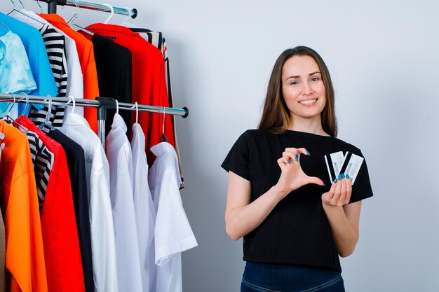 Holding credit cards girl si showing size gesture on clothes background