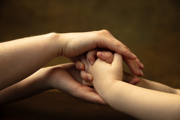 Holding hands, clapping like friends. Close up shot of female and kid's hands doing different things together. Family, home, education, childhood, charity concept. Mother and son or daughter, wealth.