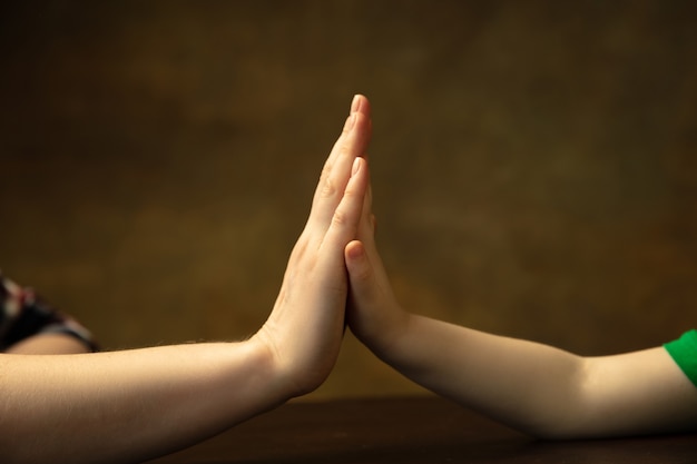 Holding hands, clapping like friends. Close up shot of female and kid's hands doing different things together. Family, home, education, childhood, charity concept. Mother and son or daughter, wealth.