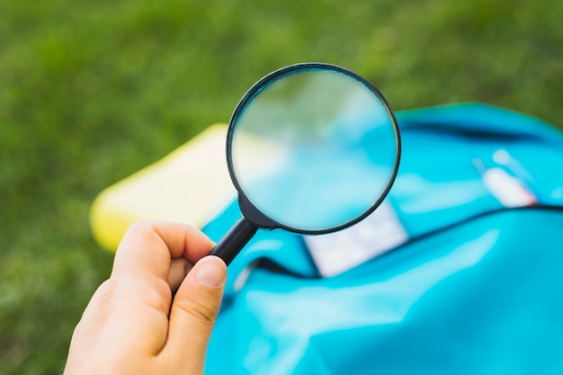 Free Photo holding magnifier increases background of backpack on grass