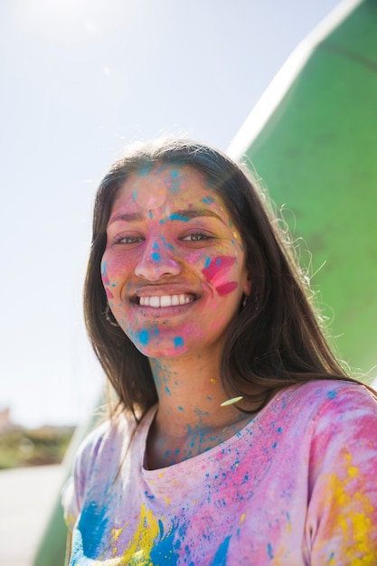 Free Photo holi color powder over the smiling young woman's face looking at camera