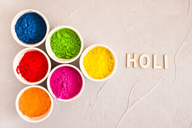 Free photo holi text near the different type of color powder on concrete background