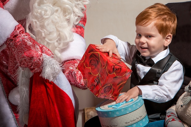 Holidays, celebration, childhood and people concept. smiling little boy with santa claus