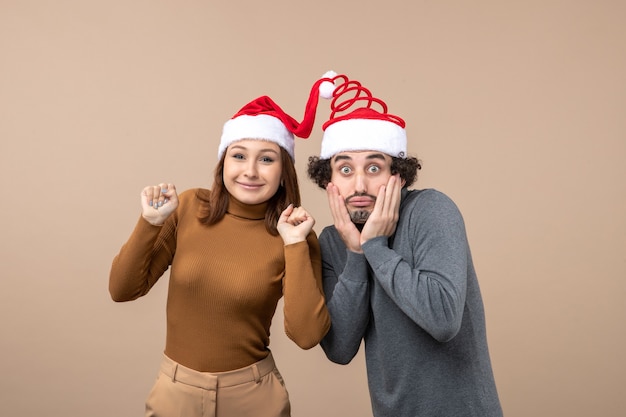 Holidays festive and party concept - happy lovely surprised young couple wearing united each other santa claus