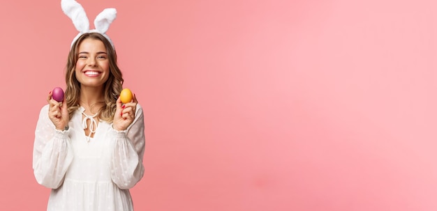 Free photo holidays spring and party concept portrait of lovely cheerful blond girl in rabbit ears holding colored eggs celebrating easter with family enjoying spend traditional day with close people