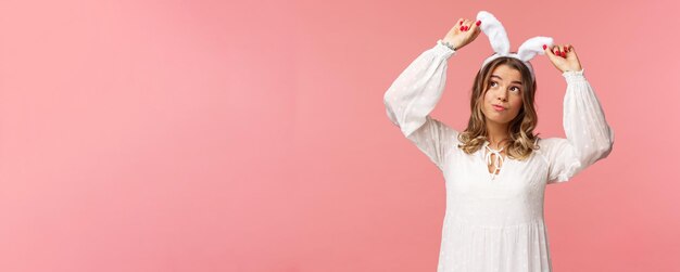 Holidays spring and party concept portrait of silly cute blond girl in rabbit ears looking up daydre