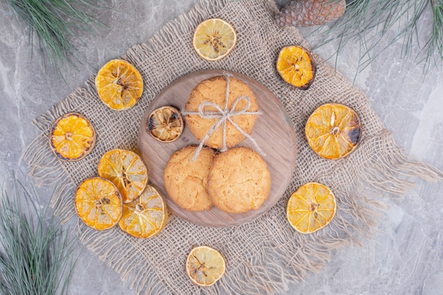 Holland waffles and cookies on a wooden board with dry orange slices around.