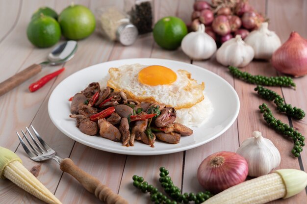 Holy Basil Fried Rice with Chicken Heart and Fried Egg on a White Wooden Floor.