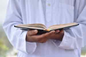 Free photo holy quran in hand with arabic calligraphy meaning of al quran.