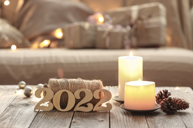 Free photo home christmas composition with decorative wood 2022 numbers, candles, and decor details on a blurred room interior background.