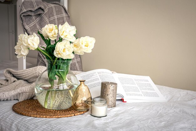 Home composition with a bouquet of tulips in a glass vase and candles