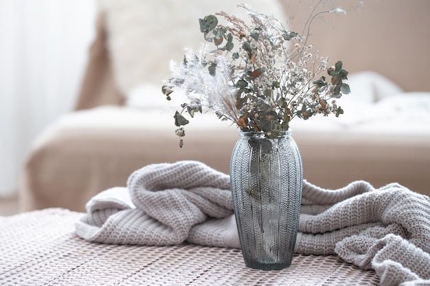 Free Photo home composition with a glass vase with dried flowers on a blurred background