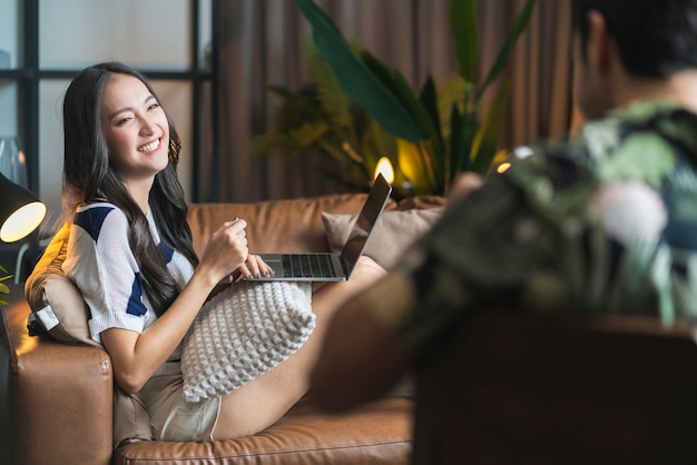 Home isolation together asian female laugh smilie conversation with her caucasian husband at living roomfamily relation home quarantine ideas concept