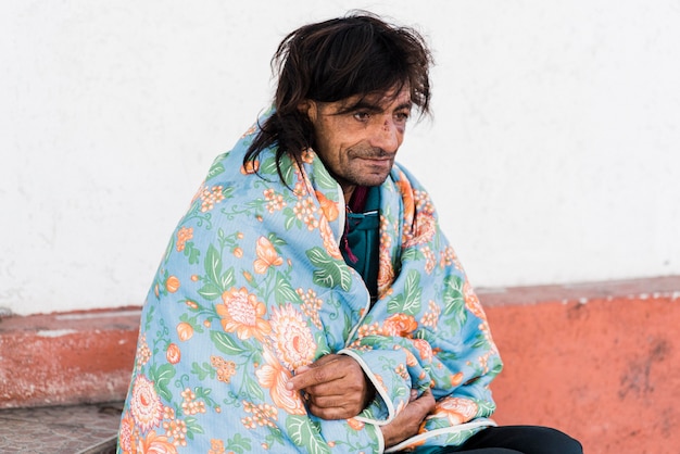 Free photo homeless man outside under blanket