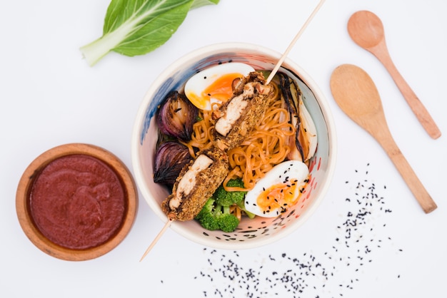 Free photo homemade asian japanese food with sauce; wooden spoon and sesame seeds on white backdrop