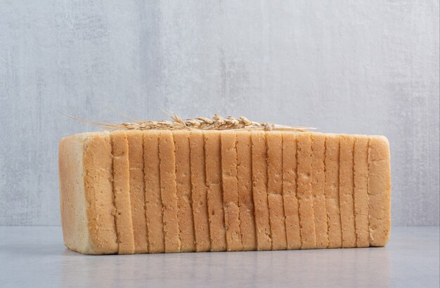 Homemade bread slices on stone surface with wheat