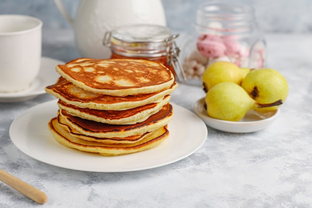 Free photo homemade breakfast: american style pancakes served with pears and honey with a cup of tea on concrete . top view and copy