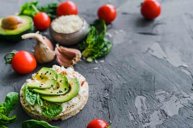 Homemade breakfast with cherry tomato; garlic; avocado and raw rice on background