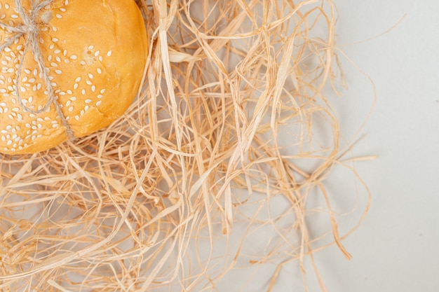 Free photo homemade bun with seeds tied with rope placed on hay